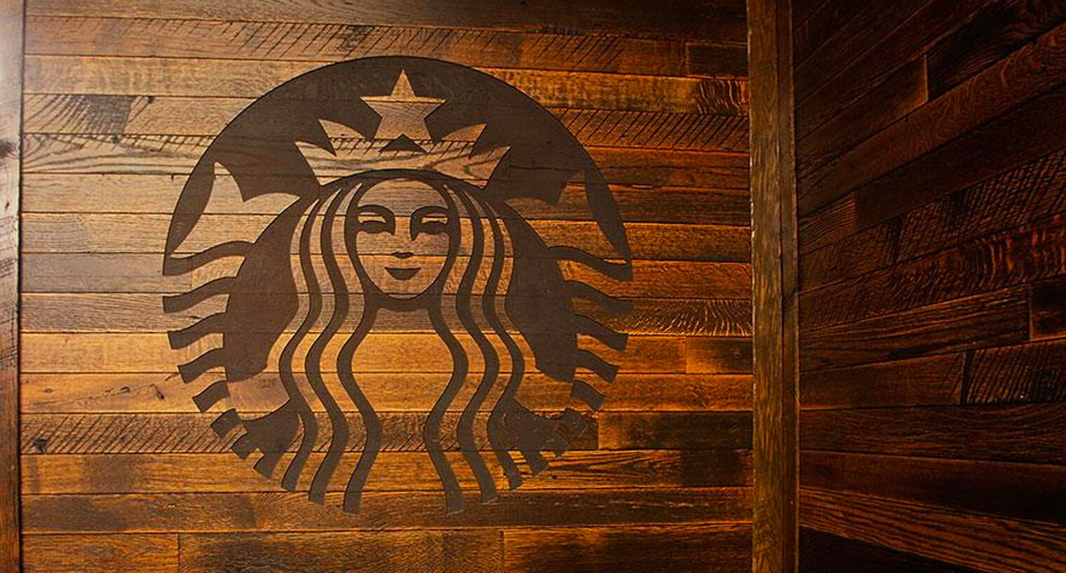wood wall corner with large dark starbucks logo