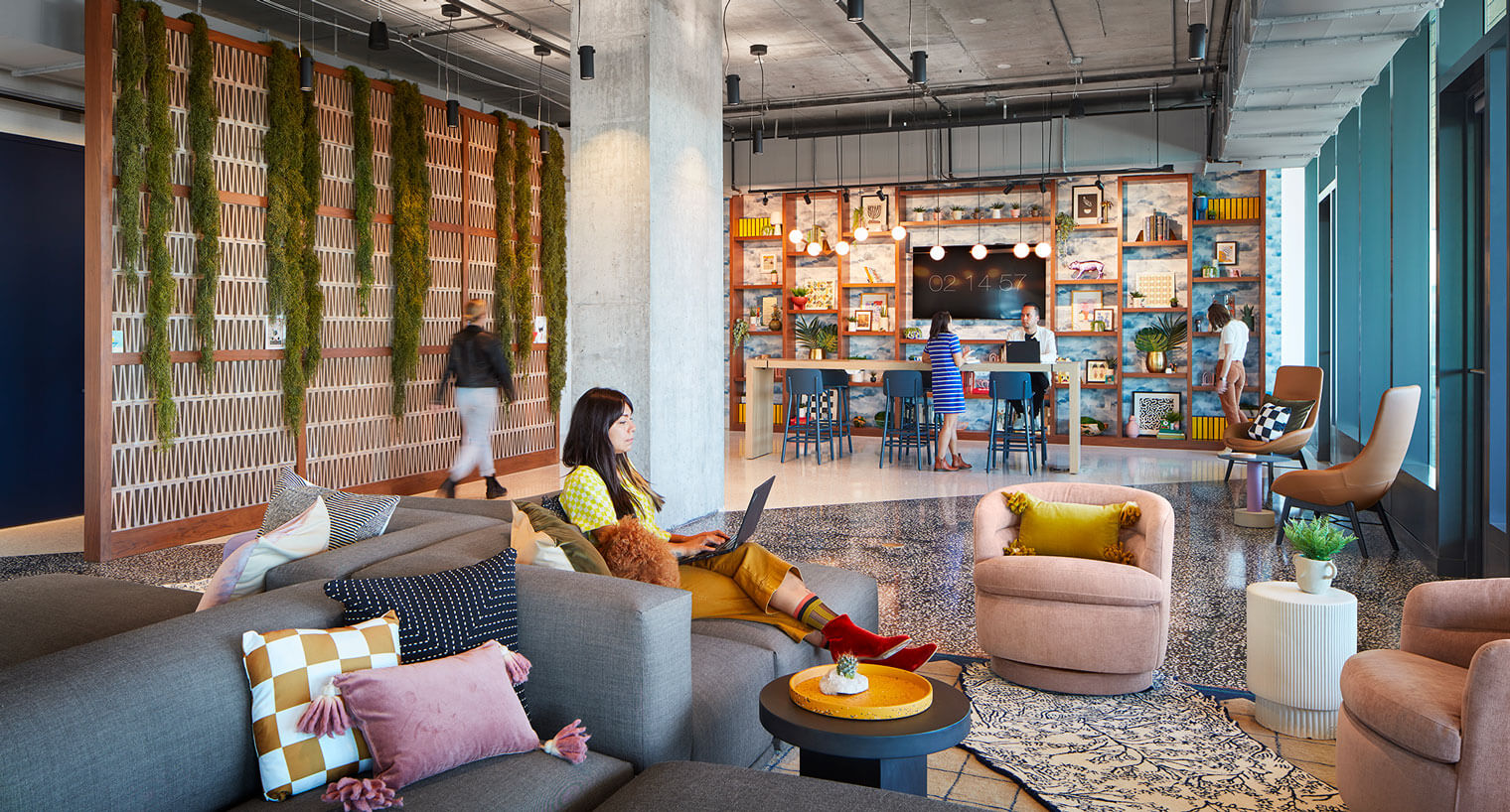 Woman on laptop uses communal seating area with decorative shelves