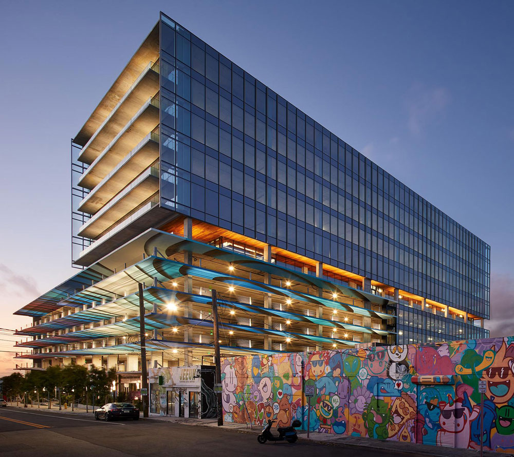 Modern glass commercial building with mural wall at sunset